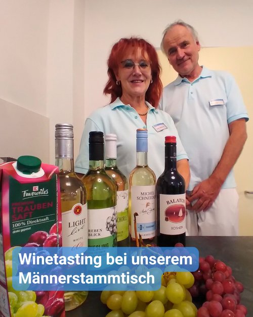 Zwei Betreuungskräfte präsentieren Weintrauben, Traubensaft und alkoholfreien Wein. Bildbeschriftung: “Winetasting bei unserem Männerstammtisch”
